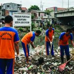 Beberapa narapidana membersihkan kali/sungai dalam program pembinaan lingkungan.