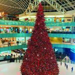 Pohon Natal megah dihias dengan lampu dan ornamen di tengah pusat perbelanjaan.